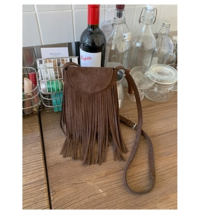 Gros plan du sac à bandoulière marron foncé à franges avec texture en daim sur bois