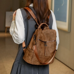 Detail of brown faux suede backpack featuring stylish fringe tassel and adjustable straps