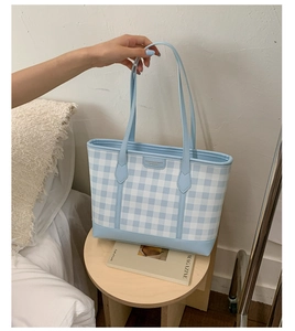 Detail of blue and white checkered tote bag featuring a leather patch on a canvas surface