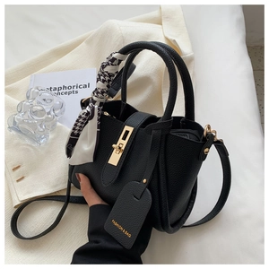 Détail du sac seau en cuir noir avec fermoir doré et foulard en soie pied-de-poule