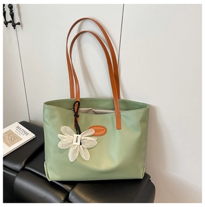 Minimalist light green faux leather tote bag with orange handles and white floral charm