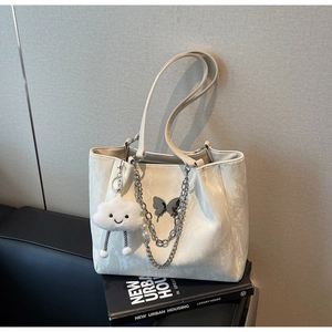 Detail of off-white tote bag with silver butterfly badge, chains and pearl charm