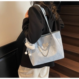 Detail of light blue pleated tote bag with pearl chain and cloud charm on a model