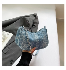 Detailed close-up of light blue denim crescent bag with silver chain and sequin finish