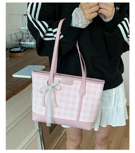 Detail view of plaid tote bag with lace bow, pearl charms and pink leather handles