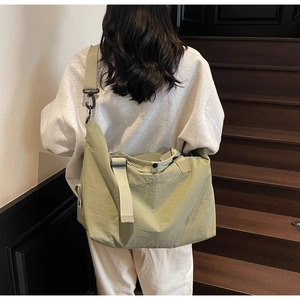 Close-up of olive green nylon travel bag featuring wide strap and brand embroidery
