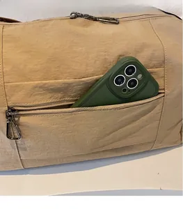 Detail of exterior zipper pocket on canvas bag with a smartphone inside for size scale