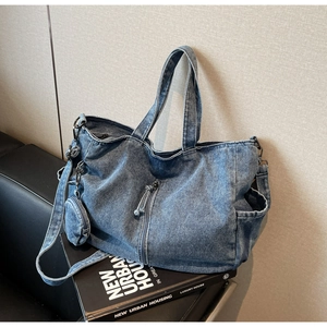 Detail of blue denim tote bag with round coin purse on a book against leather background