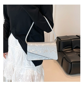 Silver snakeskin textured baguette bag with asymmetric flap shown on a model