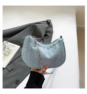 Detail of light blue denim crescent bag with sparkling rhinestones and silver chain