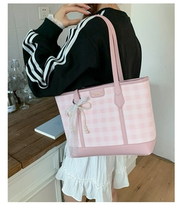 Detail of pink and white checkered tote bag with pearl bow charm and leather straps