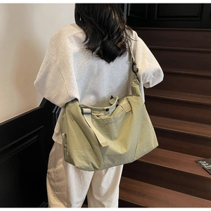 Sage green large travel bag with adjustable strap shown worn on a model's shoulder