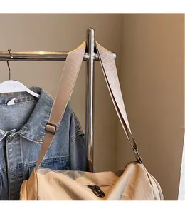 Detail of adjustable wide shoulder strap and smooth zipper on beige canvas pillow bag