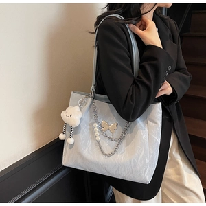Detail of light blue tote bag with pearl chain strap and silver butterfly charm