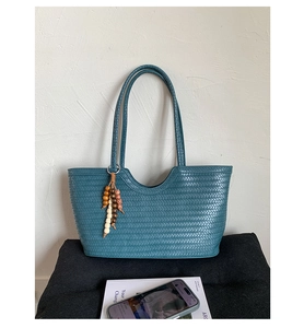 Detailed weave pattern of dark teal tote bag featuring ethnic wooden bead tassel