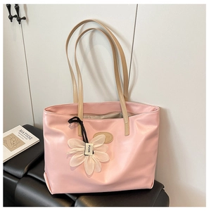 Detail of a large pink tote bag with beige straps and a white floral charm accessory