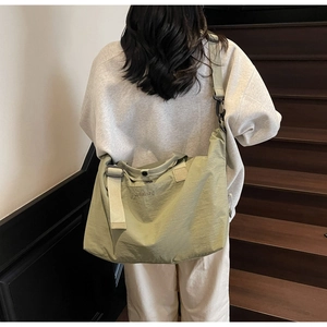 Green nylon travel bag with wide adjustable shoulder strap and brand logo detail