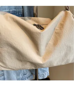 Detail of a beige canvas tote bag showing the lightweight wrinkled texture and metal zipper