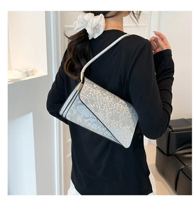 Detail of silver snake skin pattern handbag featuring an asymmetric geometric flap cover