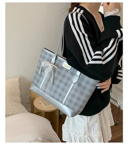 Detail of silver gingham tote bag featuring delicate lace bow and pearl pendant charm