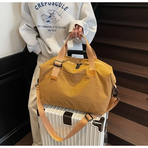 Detail of a ginger yellow travel bag with reinforced handles and brand logo on a suitcase