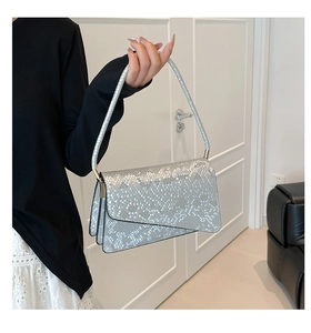 Detail of silver snake-pattern shoulder bag with metallic finish and asymmetrical flap