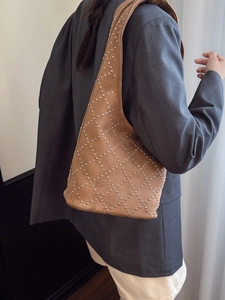 Borsa hobo in camoscio marrone con rivetti argentati e motivo a rombi indossata