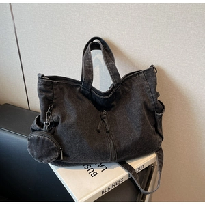 Detail of black denim tote bag with detachable shoulder strap and small round coin purse