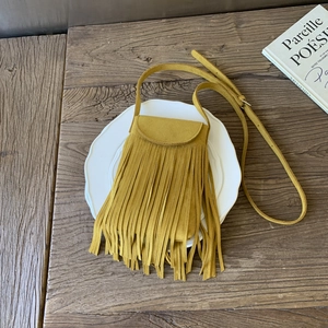 Top view of a vintage yellow fringe crossbody bag placed on a white ceramic plate
