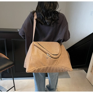 Khaki Reisetasche mit Webstruktur und verstellbarem Gurt, am Modell in einem Raum gezeigt