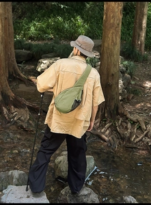 Green waterproof nylon chest bag with side mesh pocket shown in outdoor hiking setting
