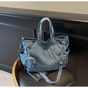 Detail of blue denim tote bag featuring vertical zipper pocket and round mini coin purse