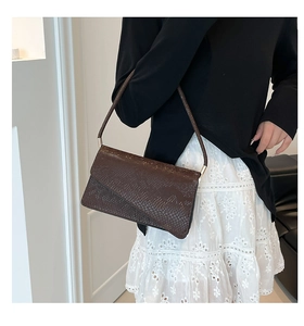 Close-up of brown snake texture leather handbag with golden metal hardware and strap