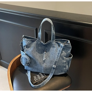 Detail of washed blue denim tote bag with round coin purse and adjustable strap