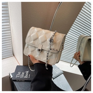 Dettaglio di una borsa a tracolla beige trapuntata con catena argento e chiusura in metallo