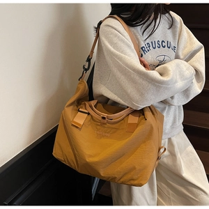 Mustard yellow travel duffel bag shown on shoulder in a lifestyle setting
