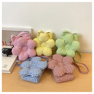 Disposition de cinq sacs bandoulière à carreaux en forme de fleur sur un bureau en bois