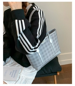 Close-up of a silver checkered tote bag on a model showing metallic texture and sleek straps