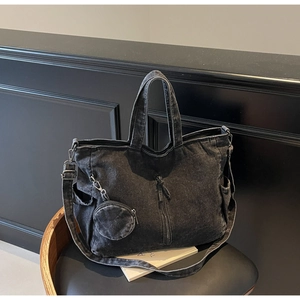 Detail of black washed denim tote bag with vertical zip pocket and small coin purse attachment
