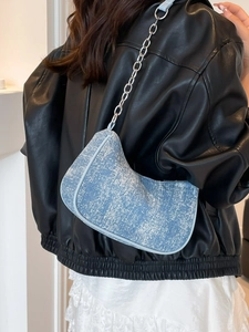 Vintage blue textured denim shoulder bag with silver chain strap worn by a model