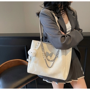 Detail of white tote bag with silver butterfly charm, pearl chain and cloud plush pendant