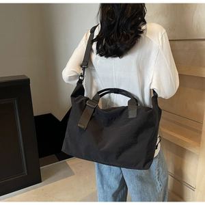 Black large capacity travel bag shown on shoulder in a modern indoor setting
