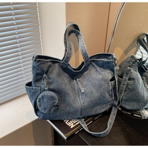 Detail of blue denim tote bag with side pockets, vertical zipper and mini pouch charm