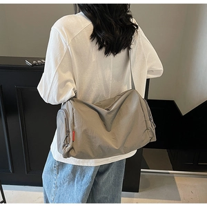 Rear view of a model wearing a large grey nylon sports bag with wide shoulder strap