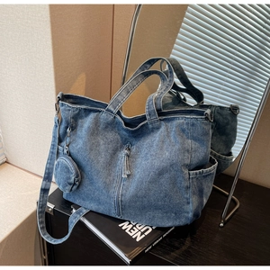Detailed view of blue denim tote bag with tassel zipper, side pockets and round coin purse