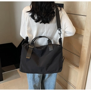 Large black travel bag shown on shoulder, featuring durable nylon and wide strap