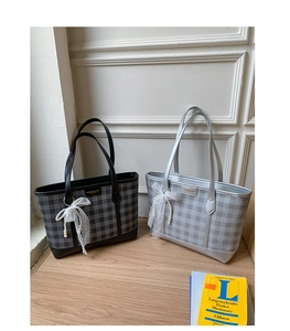 Detail of checkered tote bag with lace bow, pearl charm and leather trim craftsmanship
