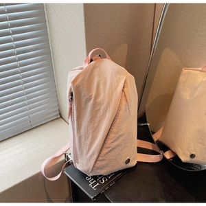 Detail of light pink canvas backpack featuring unique diagonal zippers and crinkled texture