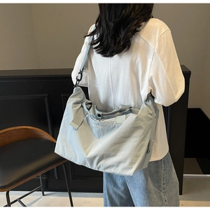 Rear view of a light blue large travel bag showing size scale on a female model