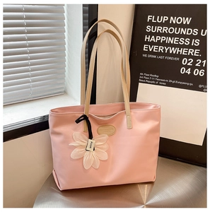 Detail of pink nylon tote bag with leather logo patch and a white floral charm accessory